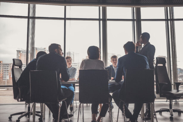 A diverse group of people sits around a conference table in a modern office, with cityscape views through large windows, conveying a professional tone.