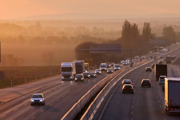 Traffic moves along a highway at sunset, with trucks and cars travelling through a hazy rural landscape.