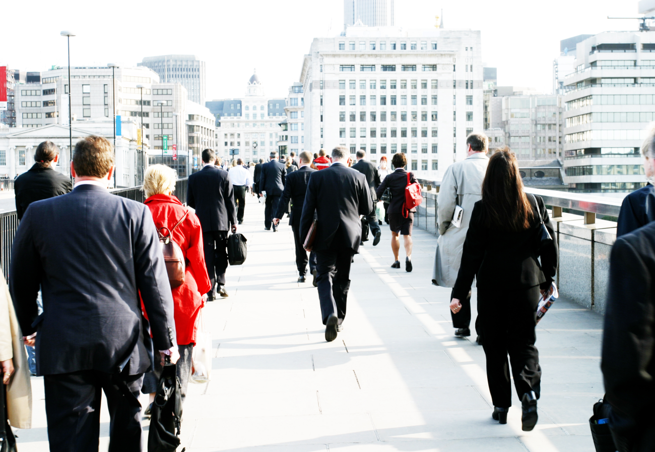 Several people walking across a bridge in business attire.