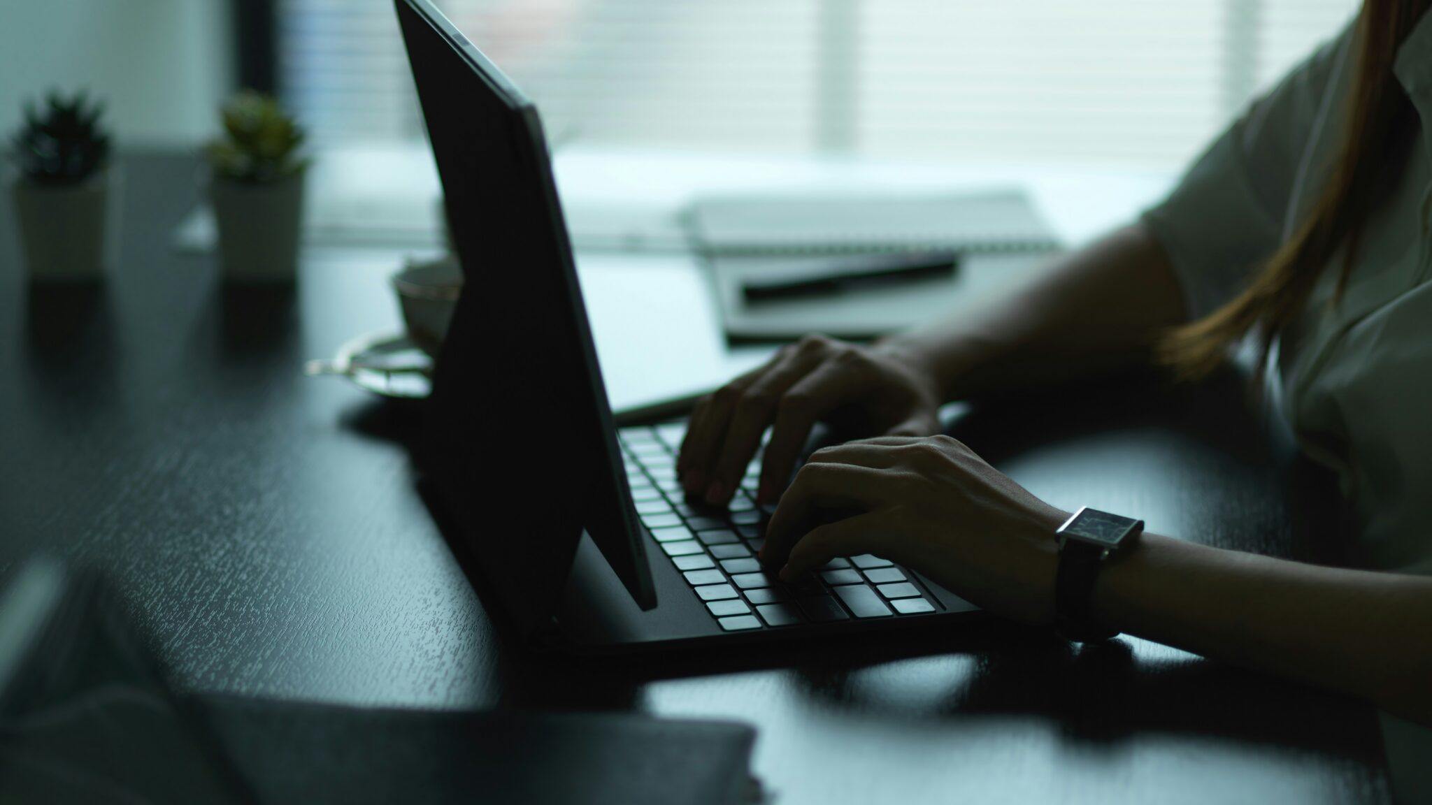 A woman uses a laptop in a dimly lit room.