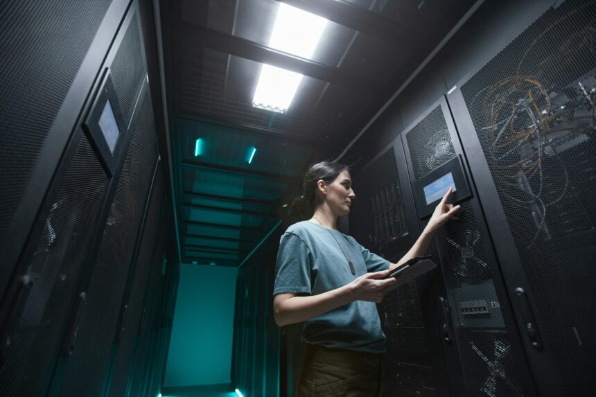 echnician using a touchscreen control panel while inspecting server racks inside a data centre.