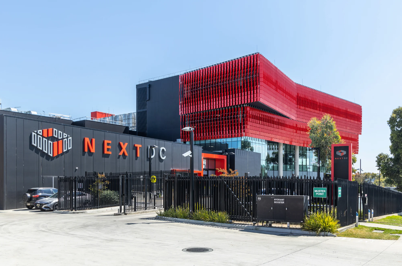 Exterior of a NEXTDC data centre featuring a distinctive red facade and NEXTDC signage.