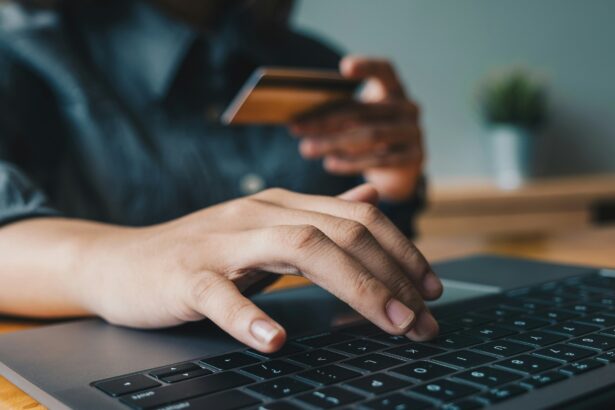 Close-up of a person typing on a laptop while holding a credit card, illustrating online shopping and digital payments.